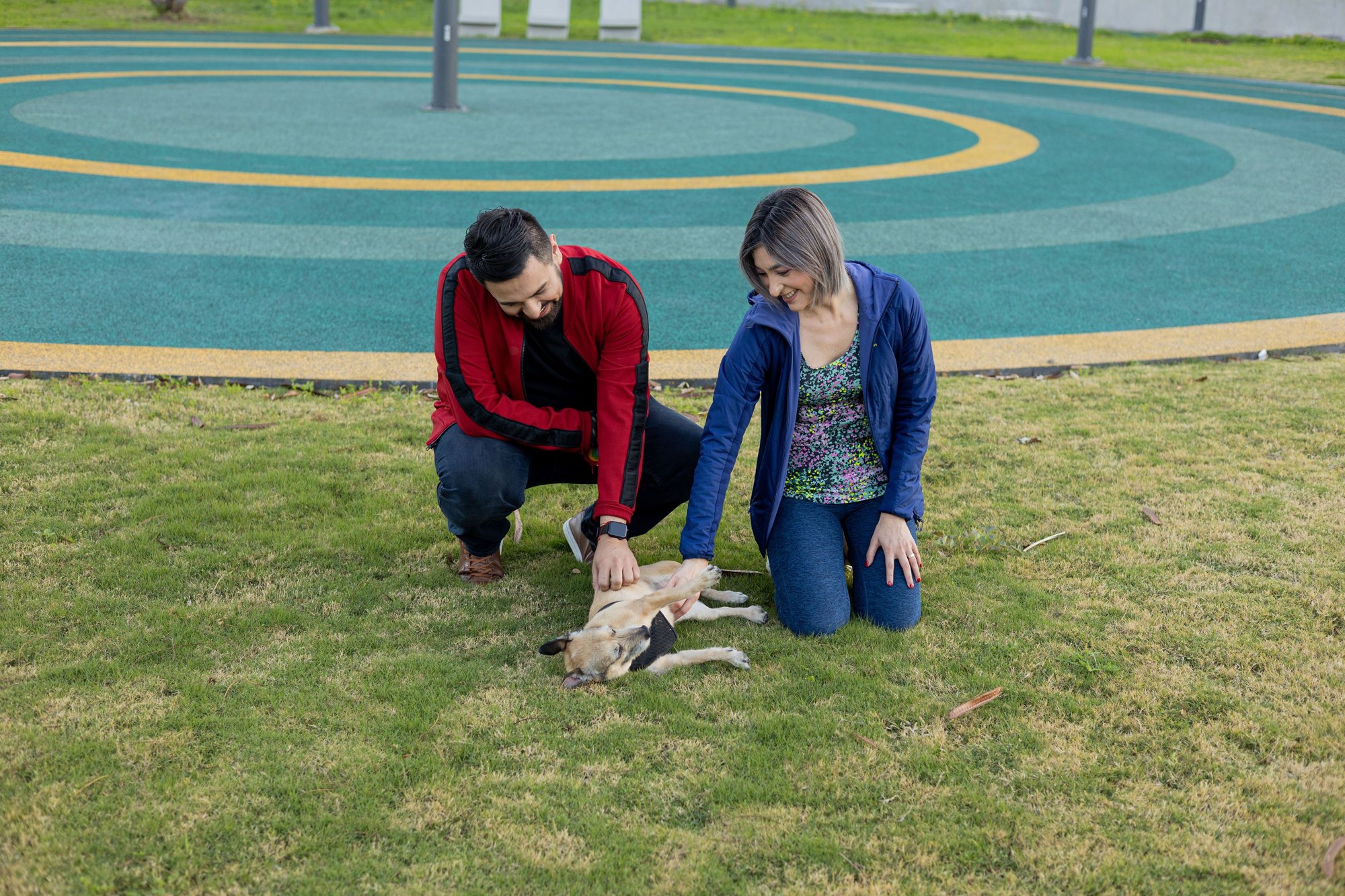 Una pareja con su perro en el césped circular del parque de Esfera